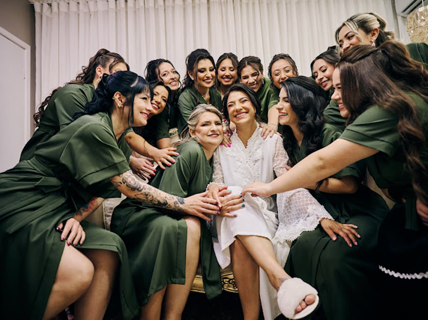 Noiva cercada pelas madrinhas de robe verde durante a preparação no Studio