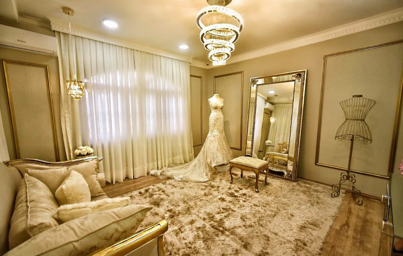 Sala da noiva em tons dourados com espelho, manequim e vestido de noiva