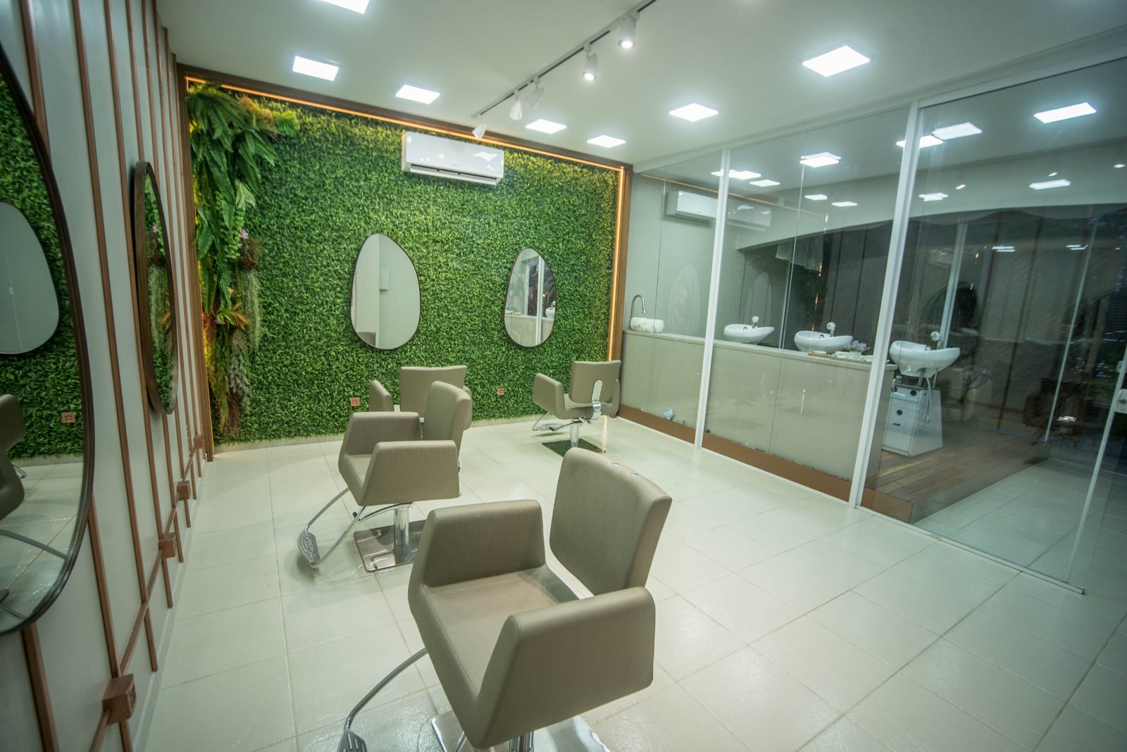 Sala verde do Studio com parede de folhagem e espelhos redondos